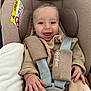baby, car_seat, smiling, child, infant, seatbelt, clothing, blanket, hand, face, happy, safety, padding, person, cute, young_child, indoors, baby_clothes, car_safety, infant_seat