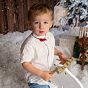 Jimy participe au concours pour gagner de l'argent avec cette photo : child, boy, white_shirt, red_bow_tie, rocking_horse, snow_effect, christmas_gifts, holiday_decor, reindeer_decoration, wooden_wall, festive, indoor, portrait, cute, winter_theme, holiday_photo, present, decorations, young_child, celebration