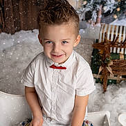 Tyago participe au concours pour gagner de l'argent avec cette photo : child, boy, smiling, white_shirt, red_bow_tie, winter, snow, holiday, christmas_gifts, decorations, wooden_wall, indoor, portrait, festive, happy, cute, seasonal, celebration, sitting, cozy