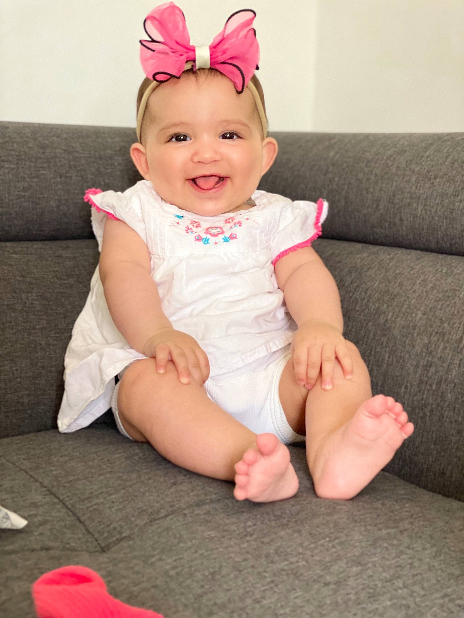 Sylia participe au concours pour gagner de l'argent avec cette photo : baby, baby_toddler_clothing, costume_hat, couch, dress, facial_expression, happy, headband, headpiece, human_body, human_leg, joy, knee, person, pink, red, skin, sleeve, smile, thigh