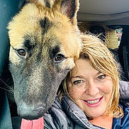 Winston is registered to the contest to win money with this photo: dog, person, smile, tongue, car_interior, closeup, face, happy, pet, companion, window, seatbelt, jacket, blond_hair, fur, ears, eyes, tongue_out, portrait, indoors