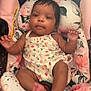 baby, infant, child, car_seat, floral_pattern, clothing, person, face, arms, legs, pink, white, comfort, relaxation, indoors, cute, young_child, seat, portrait, infant_clothing