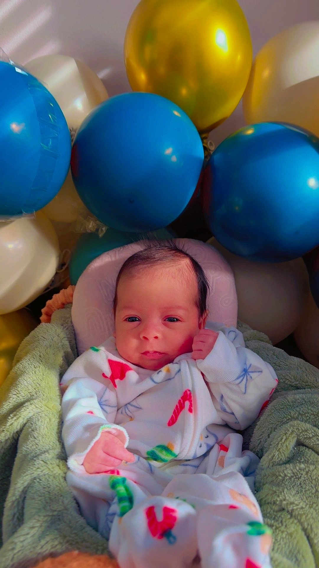 Taim is registered to the contest to win money with this photo: baby, balloons, blanket, blue_balloons, celebration, child, colorful, cozy, cream_balloon, cute, face, gold_balloon, hand, indoor, infant, newborn, pajamas, portrait, smiling, soft