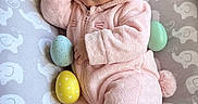 Nova is registered to the contest to win money with this photo: baby, infant, sleeping, pink_onesie, bunny_ears, cushion, elephant_pattern, easter_eggs, yellow_egg, blue_egg, green_egg, cozy, cute, soft_texture, child, adorable, resting, indoors, portrait, newborn