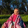 toddler, child, blanket, pink, outdoor, grass, trees, sunlight, smile, happy, nature, blue_sky, cute, sitting, clothing, portrait, baby, daylight, warm, playful