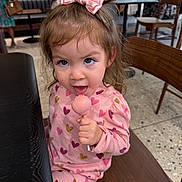 Marisa Galindo is registered to the contest to win money with this photo: toddler, child, girl, pink, pajamas, bow, lollipop, candy, sitting, chair, indoor, table, wooden, face, happy, cute, clothing, pattern, person, playful