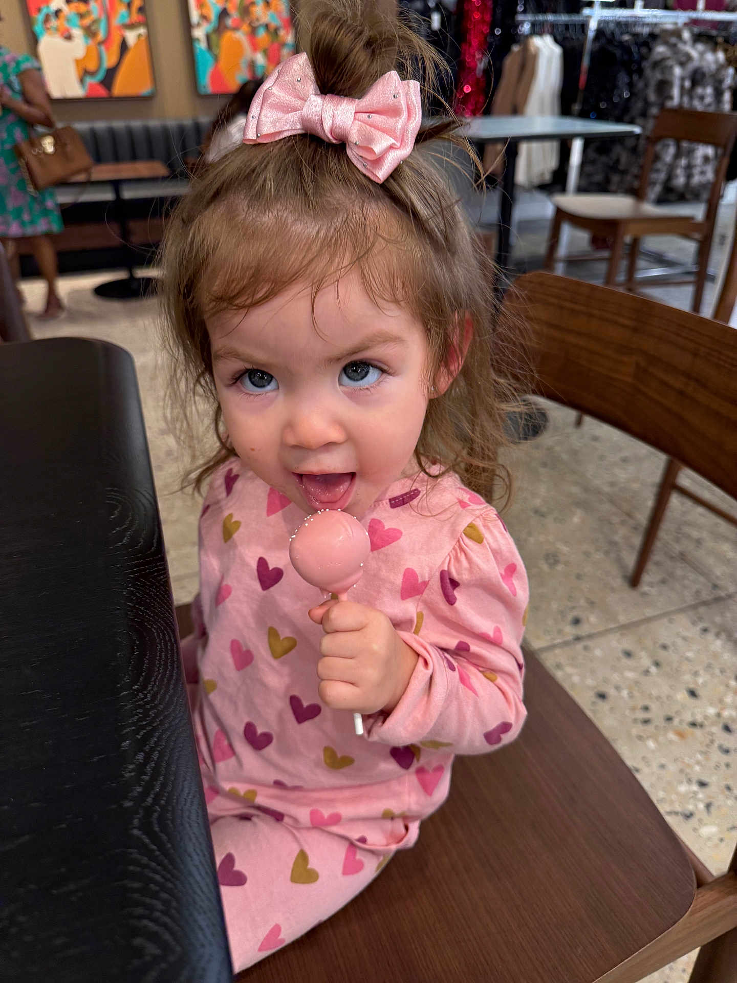 Marisa Galindo is registered to the contest to win money with this photo: toddler, child, girl, pink, pajamas, bow, lollipop, candy, sitting, chair, indoor, table, wooden, face, happy, cute, clothing, pattern, person, playful