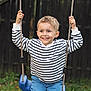 active, blue_swing, boy, casual_clothing, child, daylight, fence, fun, grass, happy, leisure, nature, outdoor, playground, portrait, ropes, short_hair, smiling, striped_shirt, swing