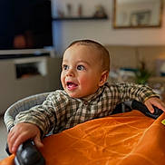 Ezio a rejoint le concours — aidez-le/la à gagner de superbes lots ! baby, infant, toddler, child, portrait, smiling, checkered_shirt, highchair, hands, eyes, cheeks, indoors, living_room, bokeh, warm_lighting, furniture, tablecloth, curiosity, candid, young