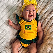 Kinsley joined the competition — help win amazing prizes! baby, infant, smiling, yellow_clothing, headband, bow, blanket, lying_down, cute, happy, face, tongue_out, green_clothing, child, portrait, cheerful, soft_texture, indoors, one_person, skin