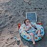 Violet joined the competition — help win amazing prizes! baby, infant, sand, beach, inflatable_ring, bottle, toy, bucket, shovel, letter_board, outdoor, sunlight, shadow, greenery, child, relaxing, summer, play, sitting, cute