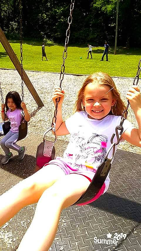 Jaylin is registered to the contest to win money with this photo: child, city, facial_expression, fun, grass, happy, human_settlement, joy, leg, leisure, outdoor_play_equipment, person, pink, play, playground, public_space, recreation, smile, summer, swing
