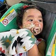 Anahi joined the competition — help win amazing prizes! child, baby, pacifier, blanket, car_seat, curly_hair, medical_tape, car_interior, seatbelt, infant, resting, toddler, cute, indoors, closeup, person, seat, warning_label, blanket_pattern, looking_away