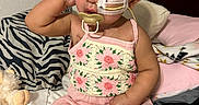 Anahi joined the competition — help win amazing prizes! baby, child, pacifier, feeding_tube, headband, flower, pink_clothing, toy, bed, pillow, blanket, cute, indoor, infant, sitting, portrait, expression, skin, hand, face