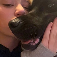 Kona is registered to the contest to win money with this photo: person, dog, black_dog, pet, cuddle, close_up, portrait, face, sleepy, closed_eyes, tongue, snout, ears, fur, hand, indoor, warm_lighting, selfie, affection, companionship