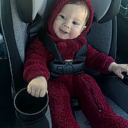 Enzo is registered to the contest to win money with this photo: baby, child, car_seat, red_onesie, hoodie, smiling, seatbelt, cup_holder, car_interior, safety, infant, happy, portrait, cozy, clothing, person, baby_fashion, seated, cute, transportation
