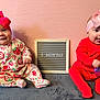 Selah And Alujah joined the competition — help win amazing prizes! babies, baby, bow, cute, grey_blanket, happy, headband, infant, milestone_board, pink_background, playful, portrait, red_outfit, sitting, smiling, strawberry_onesie, tongue_out, toy, two_babies, wall_texture