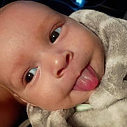 Kenny is registered to the contest to win money with this photo: baby, face, tongue, blanket, close_up, expression, cute, infant, skin, head, eyes, mouth, person, portrait, soft_texture, warm, wrapped, newborn, funny_face, indoor