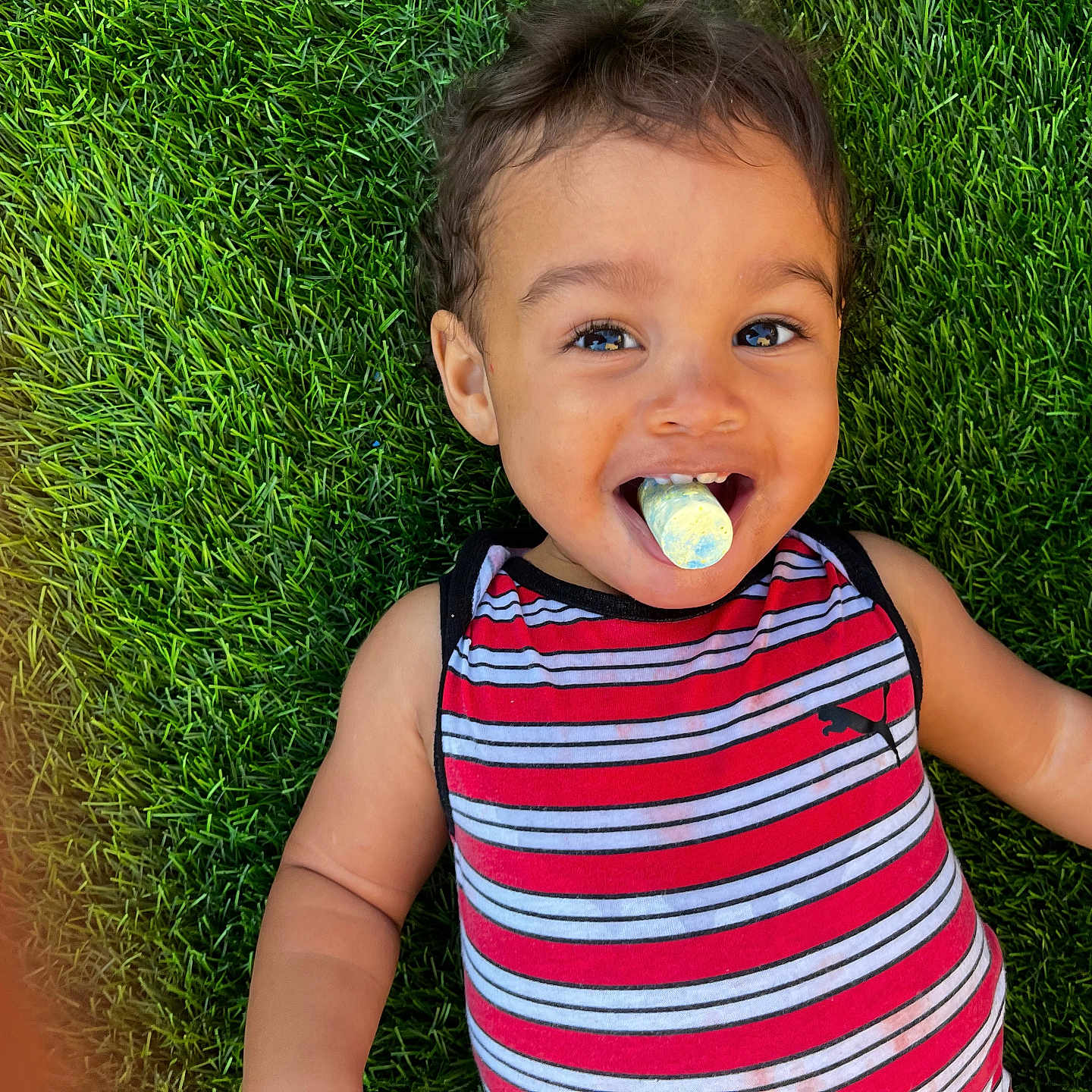 Ourlo is registered to the contest to win money with this photo: toddler, child, grass, outdoor, striped_clothing, smiling, happy, face, portrait, casual, playful, chalk, colorful, cute, young_child, summer, nature, relaxed, fun, person