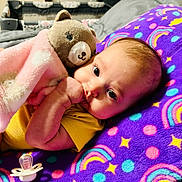 Addison is registered to the contest to win money with this photo: baby, infant, teddy_bear, blanket, purple_blanket, rainbow_pattern, stars, thumb_sucking, pacifier, yellow_clothing, cute, cozy, soft_toy, lying_down, indoor, child, face, head, sleepy, comfort