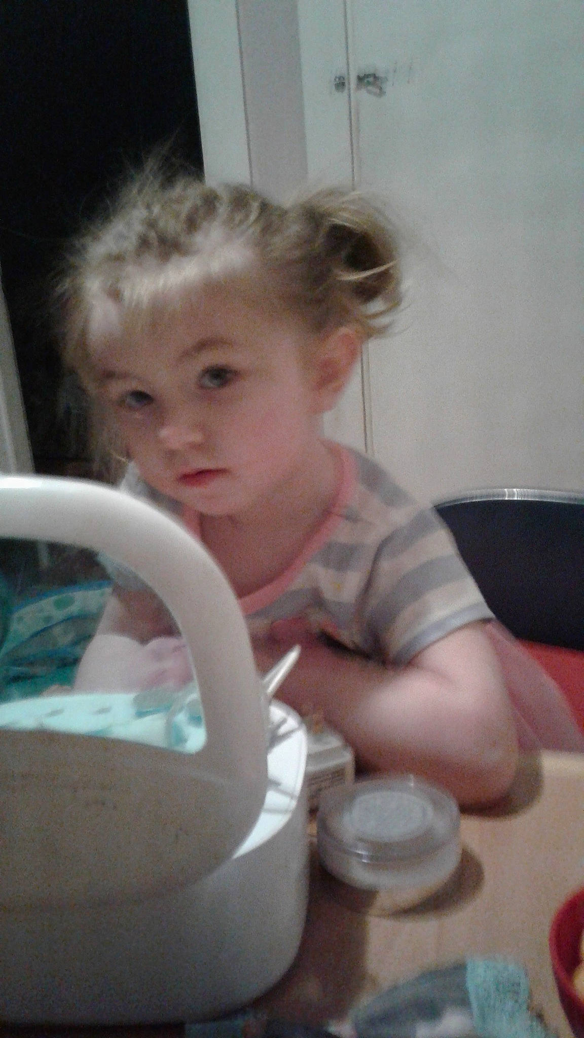 Avah is registered to the contest to win money with this photo: baby, blond, child, cup, dress, drinkware, finger, fun, glass, hairstyle, head, human_body, person, room, serveware, sitting, skin, steering_wheel, table, tableware