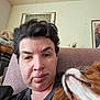 person, dog, face, hair, chair, indoor, pet, couch, portrait, looking_up, furniture, brown_hair, expressionless, closeup, domestic_animal, companion, relaxed, home, wall_art, basket