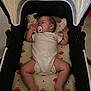 baby, sleeping, stroller, pacifier, plush_toy, cushion, infant, clothing, indoor, child, peaceful, resting, cute, person, legs, arms, head, pillow, soft, comfort