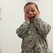 Baha participe au concours pour gagner de l'argent avec cette photo : child, smiling, sweater, dog_faces, happy, hands_on_cheeks, indoor, portrait, cute, joyful, expression, casual_clothing, young, person, face, playful, light_background, wall, fun, emotion