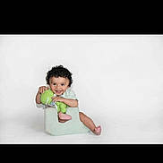 Malachi joined the competition — help win amazing prizes! child, toddler, baby, sitting, potty_chair, smiling, curly_hair, green_clothing, pink_shoes, portrait, studio, white_background, indoor, infant, playful, happy, cute, seated, photography, throne