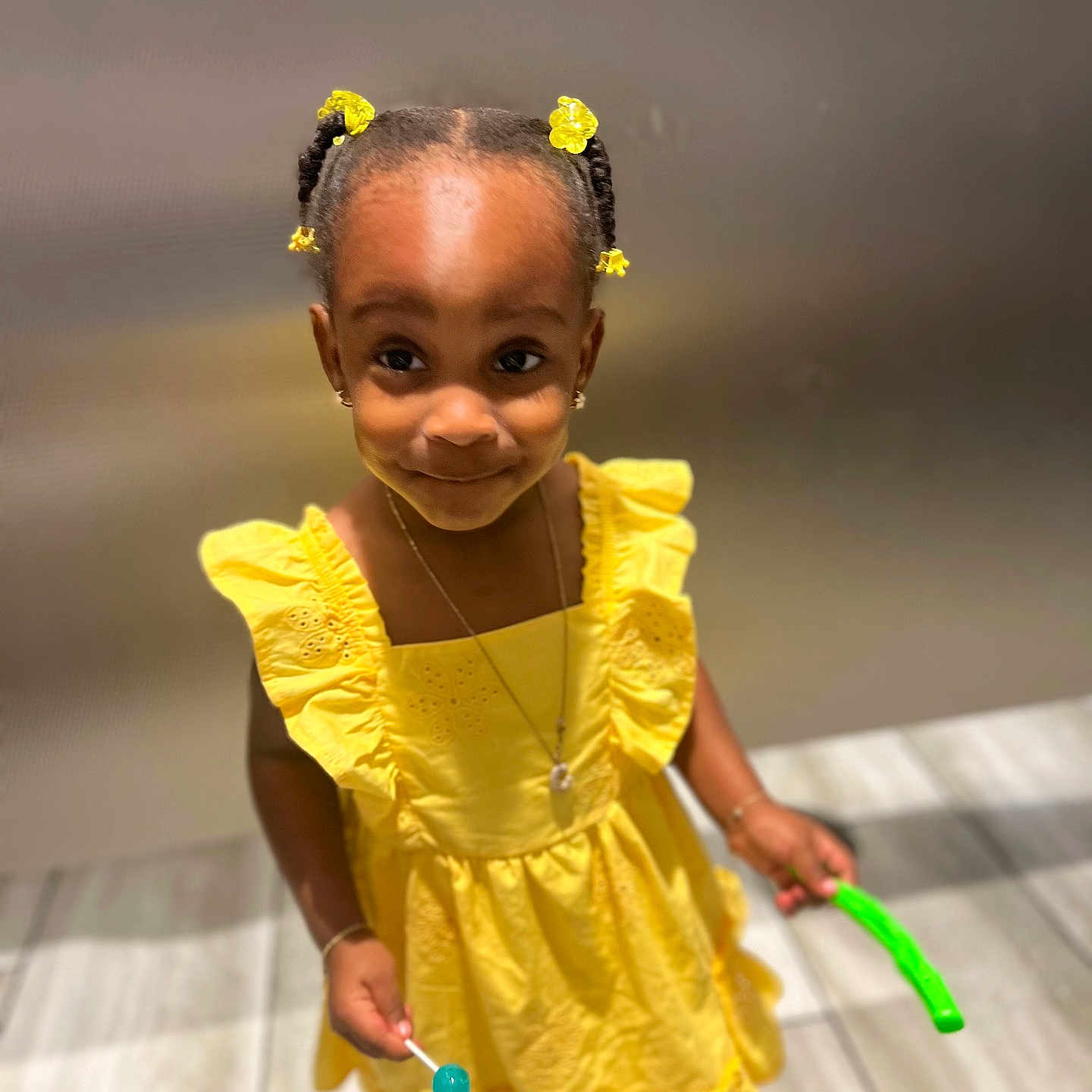 Celaní is registered to the contest to win money with this photo: bracelet, child, cute, floor, girl, hair_accessories, happy, indoor, jewelry, lollipop, necklace, person, pigtails, playful, portrait, smile, standing, tile, toy, yellow_dress