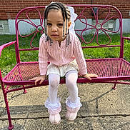 Kobi joined the competition — help win amazing prizes! child, girl, braids, beads, pink_sweater, white_skirt, white_tights, pink_boots, bench, metal_bench, flower_design, outdoor, brick_wall, grass, sidewalk, sunlight, portrait, cute, seated, curious