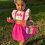 child, girl, outdoor, grass, pink_clothing, braided_hair, beads, cookie, pop_it_purse, sneakers, sunlight, tree, house, smile, fashion, accessory, playful, cute, summer, portrait