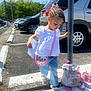 Kobi is registered to the contest to win money with this photo: child, girl, parking_lot, curb, white_blouse, jeans, pink_purse, unicorn_backpack, sippy_cup, sunny, outdoor, sidewalk, signpost, cars, hair_beads, sandals, paper, trees, daytime, balance