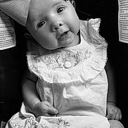 Mylan joined the competition — help win amazing prizes! baby, child, black_and_white, bow, dress, embroidery, cute, portrait, sitting, infant, clothing, sock, legs, face, headwear, adorable, expression, closeup, seat, monochrome