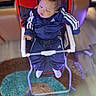 Braelin is registered to the contest to win money with this photo: baby, child, infant, high_chair, sitting, sleepy, face, curly_hair, tracksuit, sportswear, blue_clothing, red_chair, harness, indoors, living_room, rug, floor, furniture, portrait, photography