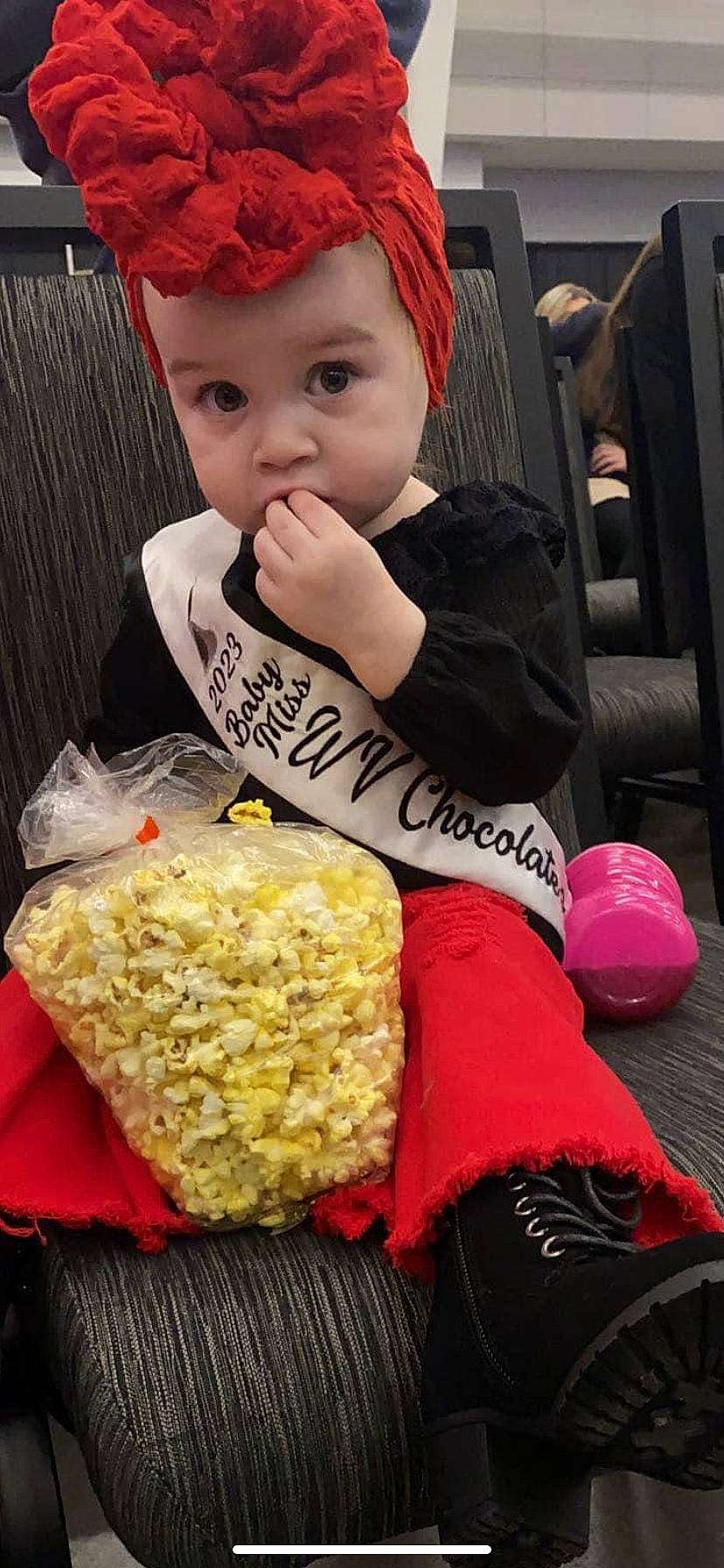 Caroline is registered to the contest to win money with this photo: baby_toddler_clothing, cap, child, comfort_food, cuisine, dish, event, food, fun, happy, headwear, ingredient, junk_food, kettle_corn, person, popcorn, recipe, rice, staple_food, sweetness