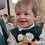 toddler, child, smiling, formal_clothing, bow_tie, vest, flower, indoor, event, people, adult, glasses, stained_glass, background, portrait, happy, hands, face, short_hair, ceremony