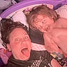 Addilynn is registered to the contest to win money with this photo: adult, bed, blanket, casual_clothing, child, childhood, closeup, cozy, family, fun, hair, indoor, person, pillow, playful, portrait, purple_bed_frame, silly_faces, smile, stuffed_animals