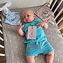 Aylan participe au concours pour gagner de l'argent avec cette photo : baby, blanket, blue_clothing, card, child, crib, cute, face, furniture, hand, indoors, infant, legs, pale_skin, shirt, shorts, sleeping_area, soft_toy, stuffed_animal, wood_floor