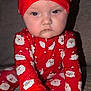 Freya is registered to the contest to win money with this photo: baby, child, pajamas, red_clothing, santa_claus, hat, face, hand, couch, indoor, person, infant, holiday, christmas, cute, expression, sitting, young_child, portrait, holiday_clothing