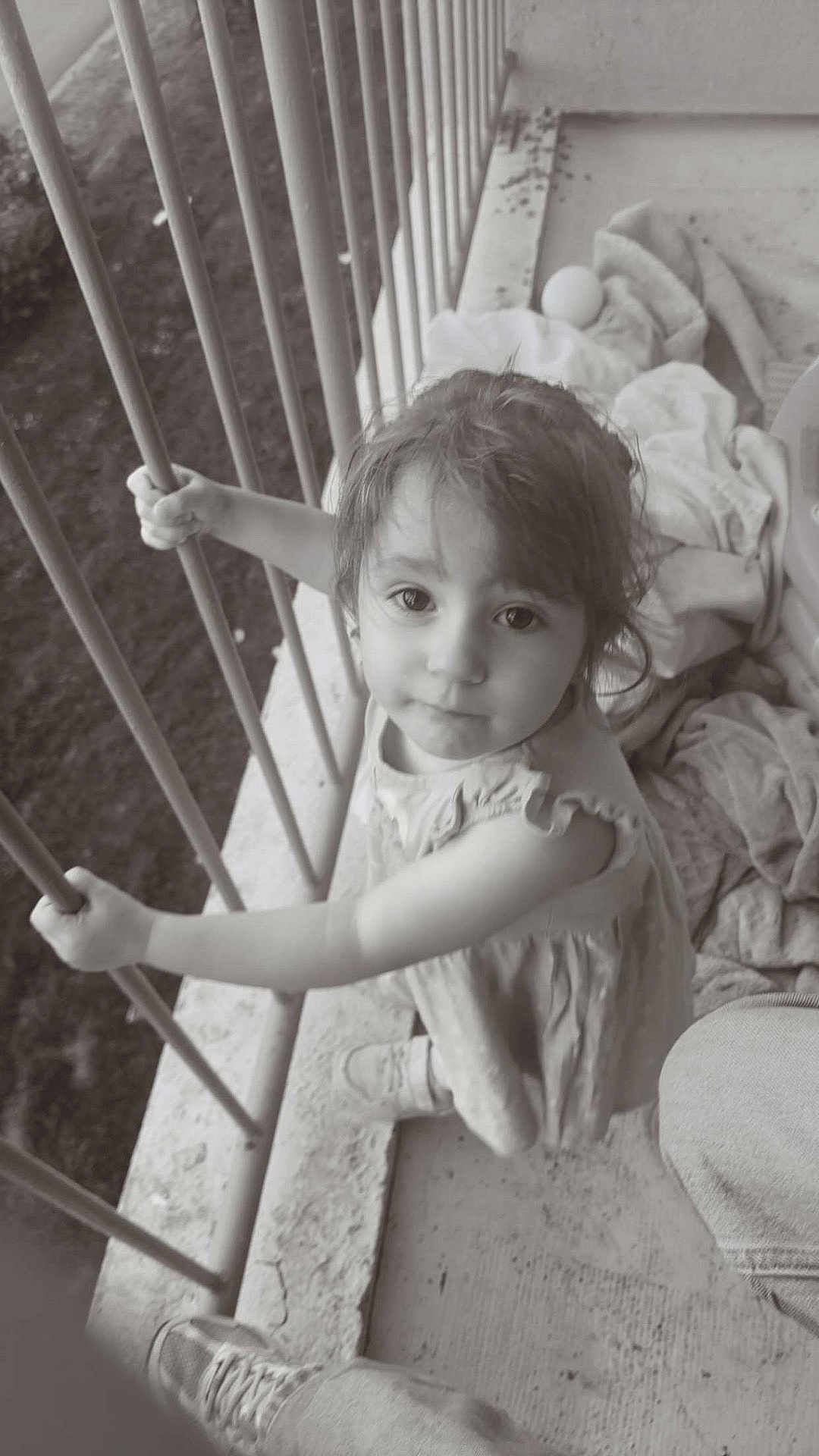 Kessy a rejoint le concours — aidez-le/la à gagner de superbes lots ! child, girl, balcony, railing, black_and_white, curious, looking_up, playful, ball, blanket, outdoor, concrete, clothing, shoe, person, portrait, young, cute, innocent, grip
