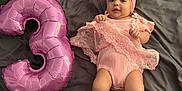 Elia a rejoint le concours — aidez-le/la à gagner de superbes lots ! adorable, baby, balloon, blanket, celebration, child, clothing, cute, feet, hands, headband, indoors, infant, lying_down, number_three, pink, portrait, skin, smile, soft_fabric