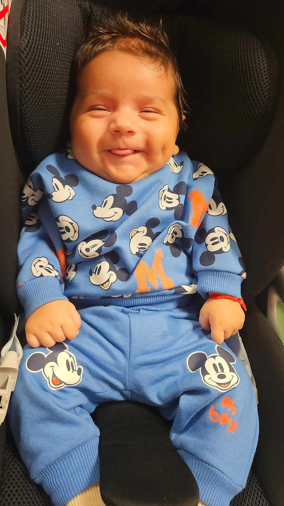 Antonio a rejoint le concours — aidez-le/la à gagner de superbes lots ! baby, child, smiling, mickey_mouse, blue_clothing, car_seat, happy, cute, infant, portrait, person, young_child, dimple, tongue_out, casual, seated, indoors, cozy, clothing_pattern, playful