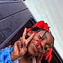 child, girl, peace_sign, braids, red_beads, red_bow, blue_flower_bracelet, car_window, smile, summer, lemon_pattern, tank_top, portrait, happy, playful, outdoor, skin, hand_gesture, accessory, youth