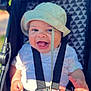 baby, smiling, bucket_hat, stroller, white_shirt, happy, child, infant, seatbelt, outdoor, patterned_background, cute, hands, face, portrait, bright, daylight, closeup, baby_clothing, joyful