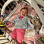 baby, crib, toy, blanket, smile, child, striped_shirt, pink_pants, soft_toy, giraffe_toy, stuffed_animal, play_gym, happy, infant, clothing, cute, indoor, person, baby_toys, bed