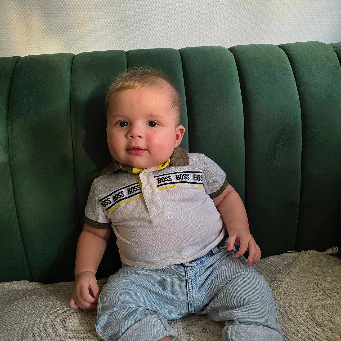 Habib Imran participe au concours pour gagner de l'argent avec cette photo : baby, casual_clothing, child, comfortable, cute, face, fashion, green_couch, home, indoor, infant, jeans, person, polo_shirt, portrait, sitting, smiling, sneakers, soft_light, young_child