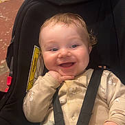 Noah is registered to the contest to win money with this photo: baby, child, car_seat, smiling, happy, blanket, indoor, seatbelt, clothing, hand, face, person, cute, infant, playful, cheerful, young, safety, seat, expression
