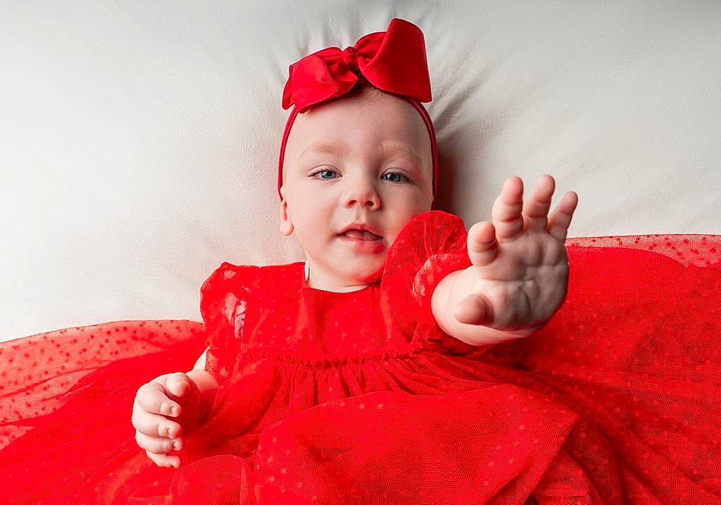 Olive is registered to the contest to win money with this photo: baby, baby_toddler_clothing, chin, comfort, costume_hat, event, eye, finger, gesture, happy, hat, head, headwear, human_body, lip, neck, peach, person, pink, sleeve