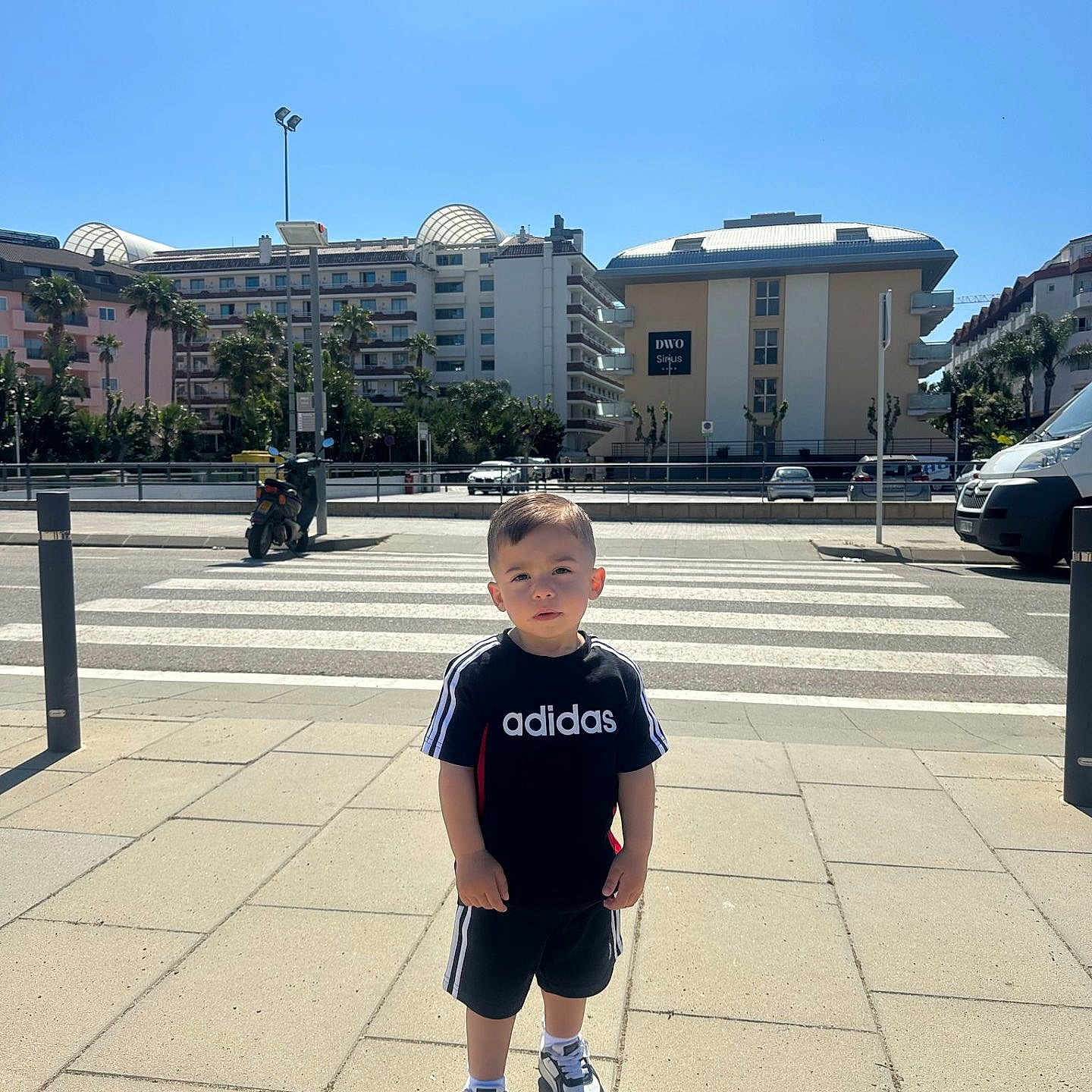 Léo a rejoint le concours — aidez-le/la à gagner de superbes lots ! adidas, boy, buildings, casual, child, crosswalk, daylight, outdoor, palm_trees, person, photography, shadow, shorts, sidewalk, sky, sneakers, sportswear, street, tshirt, urban